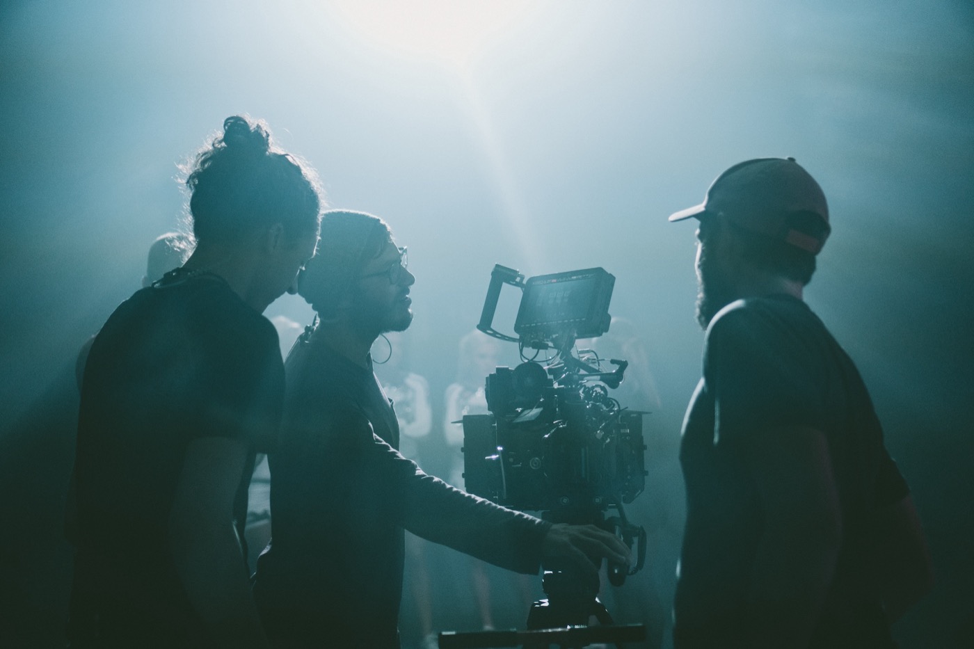 Crew silhouetted in haze around a cinema camera