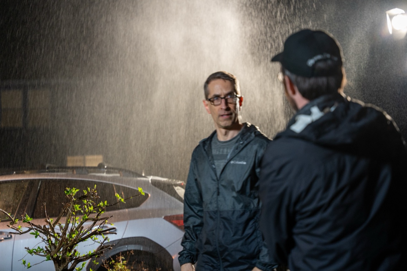 Ian Hoyt talking with a crew member under the rain rig at night